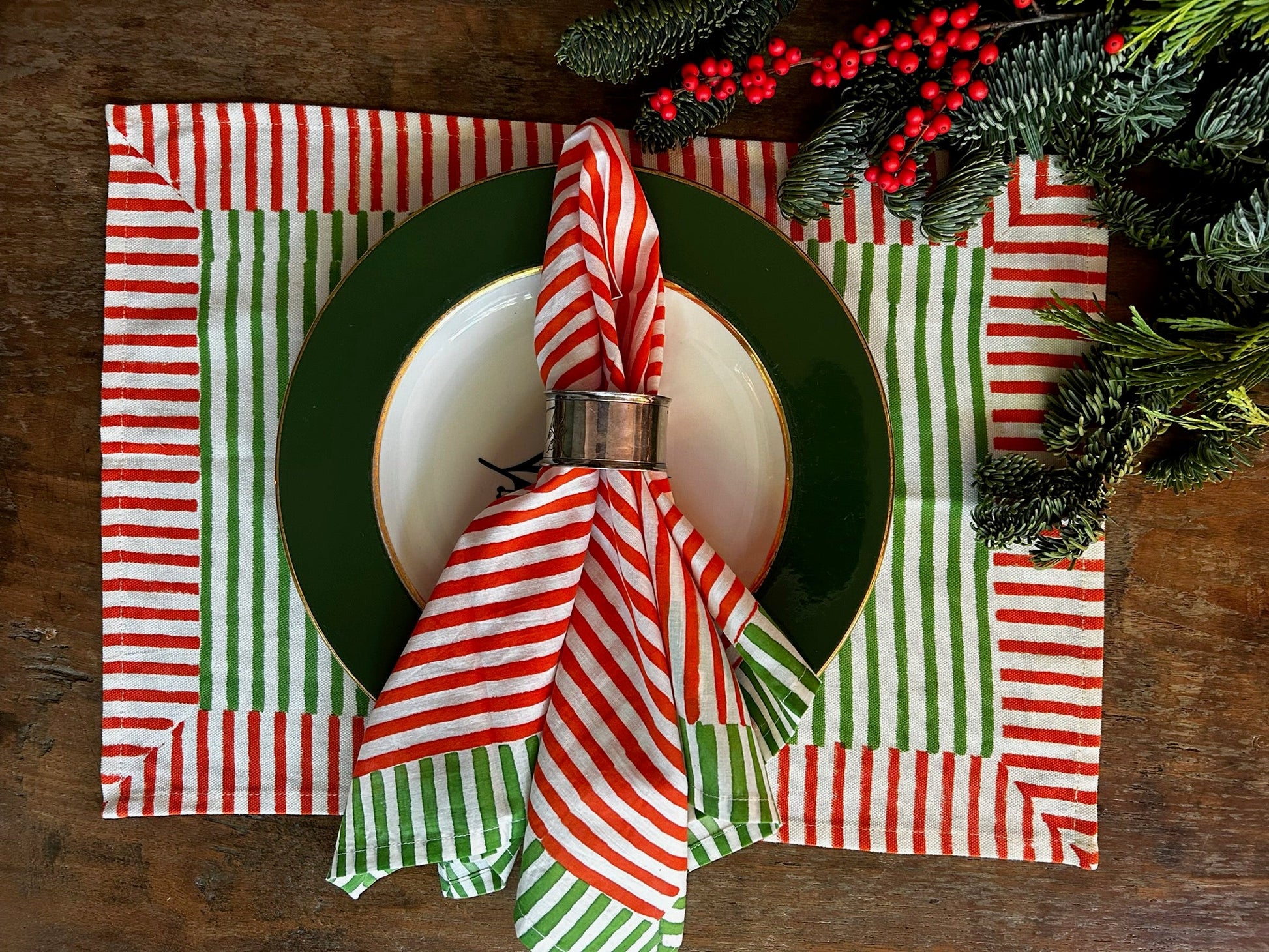Christmas-themed table setting with red and green striped napkins, a green plate, and white bowl.